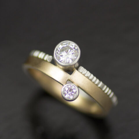 https://b3168172.smushcdn.com/3168172/wp-content/uploads/2021/07/vis-a-vis-bezel-set-moissanites-in-platinum-and-14k-yellow-gold-asymmetrical-engagement-ring-with-textured-wedding-band-480x480.jpg?lossy=0&strip=1&webp=1