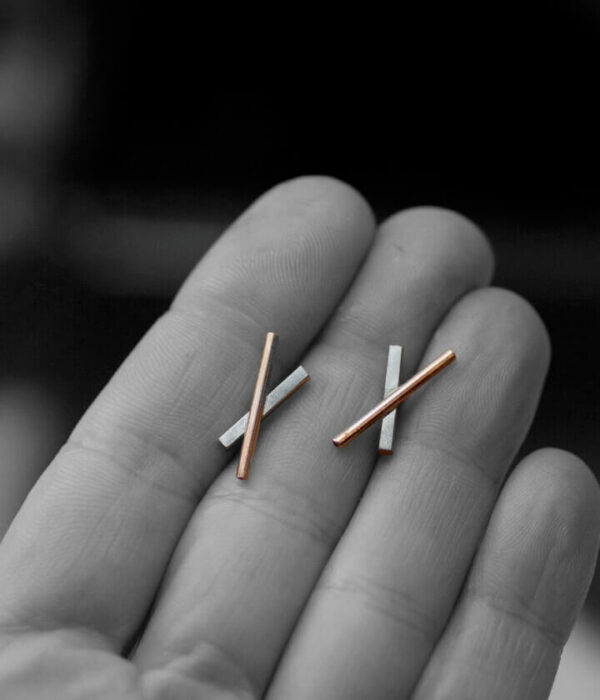 double x on hand close up mixed metals earrings