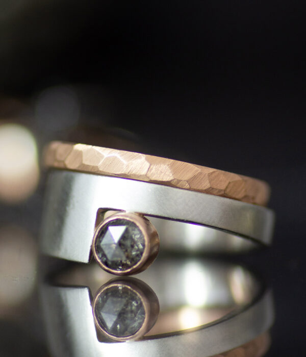 platinum and 14K rose gold non binary modern engagement ring with rose cut salt and pepper sapphire and faceted wedding band